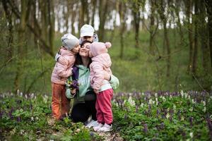contento de la madre día. nosotros amor tú, mamá. madre con un ramo de flores de flores y Tres niños en primavera floreciente bosque. foto