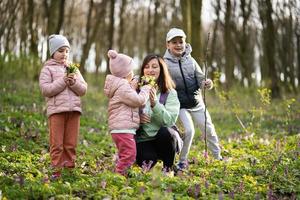 Happy Mother's Day. We love you, mom. Mother with a bouquet of flowers and three kids in spring blooming forest. photo