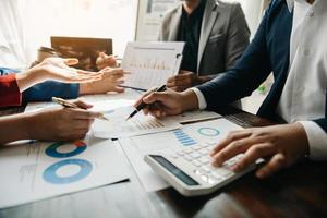 Business documents on office table with smart phone and calculator digital tablet and graph business with social network diagram and two colleagues discussing data working in the office photo