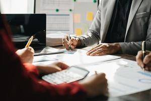 Business documents on office table with smart phone and calculator digital tablet and graph business with social network diagram and two colleagues discussing data working in the office photo