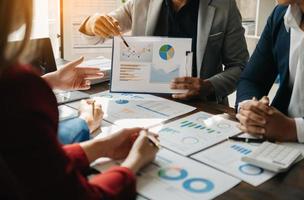 Business documents on office table with smart phone and calculator digital tablet and graph business with social network diagram and two colleagues discussing data working in the office photo