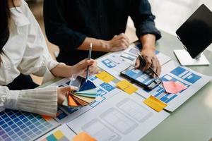 UX developer and ui designer brainstorming about mobile app interface wireframe design with customer breif and color code at office. photo
