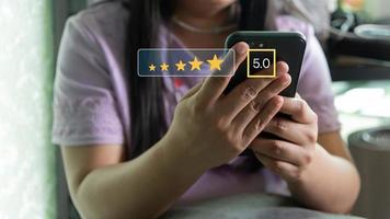 Customer service satisfaction evaluation concept. Man using smartphone and touching on screen with gold five star rating excellent feedback icon, Rated a very good review. photo