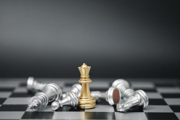 Gold king chess piece win over lying down pawn on black background