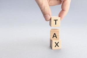 Taxation concept. Hand putting a block with TAX word on top of others. Copy space photo