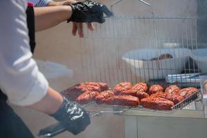 The cook prepares grilled meat patties.Grilled meat. A piece of meat in the smoke. photo