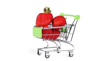 Supermarket trolley with strawberries on a white background. Sale of berries. photo