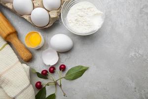Ingredients baking flour eggs rolling pin berries kitchen textiles on gray background. Cookie pie or cake recipe mockup. Background preparation for culinary baking. photo