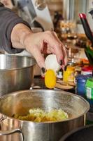 Chef cracks an egg into dish that is being prepared in bowl photo