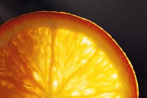 naranja rebanada macro con un soltar de agua antecedentes . jugoso naranja rebanado de cerca en un oscuro antecedentes foto