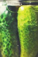 pickled cucumbers in a glass jar close. gherkins cucumbers background photo