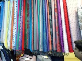 clothes in shop,Rolls of fabric and textiles for sale stacked on shelves in shop, View of cloth rolls of different colors and patterns on shelves in fabric store, colorful panoramic background photo