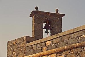 old retro vintage bell on the belfry of a stone building in spain photo