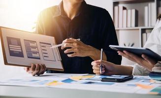 Close up ux developer and ui designer brainstorming about mobile app interface wireframe design on table with customer breif and color code at modern office.Creative digital development agency photo