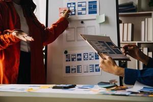 Close up ux developer and ui designer brainstorming about mobile app interface wireframe design on table with customer breif and color code at modern office.Creative digital development agency photo