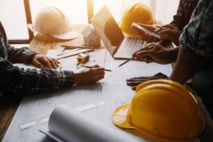 Image of engineering objects on workplace with three partners interacting on background photo