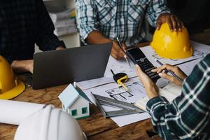Image of engineering objects on workplace with three partners interacting on background photo