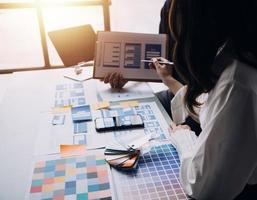 Close up ux developer and ui designer brainstorming about mobile app interface wireframe design on table with customer breif and color code at modern office.Creative digital development agency photo