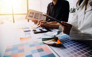 Close up ux developer and ui designer brainstorming about mobile app interface wireframe design on table with customer breif and color code at modern office.Creative digital development agency photo