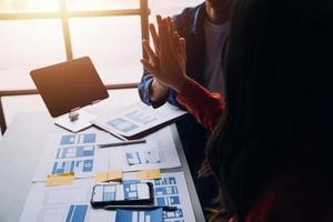 Close up ux developer and ui designer brainstorming about mobile app interface wireframe design on table with customer breif and color code at modern office.Creative digital development agency photo