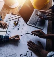 Image of engineering objects on workplace with three partners interacting on background photo