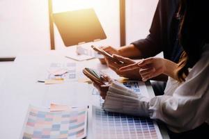Close up ux developer and ui designer brainstorming about mobile app interface wireframe design on table with customer breif and color code at modern office.Creative digital development agency photo