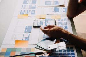 Close up ux developer and ui designer brainstorming about mobile app interface wireframe design on table with customer breif and color code at modern office.Creative digital development agency photo