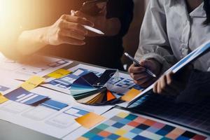 Close up ux developer and ui designer brainstorming about mobile app interface wireframe design on table with customer breif and color code at modern office.Creative digital development agency photo