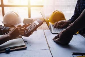 Image of engineering objects on workplace with three partners interacting on background photo