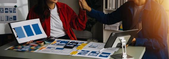 Close up ux developer and ui designer brainstorming about mobile app interface wireframe design on table with customer breif and color code at modern office.Creative digital development agency photo