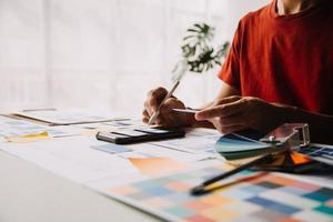 Close up ux developer and ui designer brainstorming about mobile app interface wireframe design on table with customer breif and color code at modern office.Creative digital development agency photo
