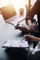 Group of confident business people point to graphs and charts to analyze market data, balance sheet, account, net profit to plan new sales strategies to increase production capacity. photo