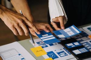 Close up ux developer and ui designer brainstorming about mobile app interface wireframe design on table with customer breif and color code at modern office.Creative digital development agency photo