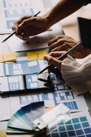 Close up ux developer and ui designer brainstorming about mobile app interface wireframe design on table with customer breif and color code at modern office.Creative digital development agency photo