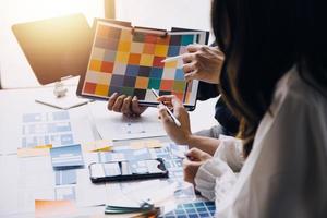 Close up ux developer and ui designer brainstorming about mobile app interface wireframe design on table with customer breif and color code at modern office.Creative digital development agency photo