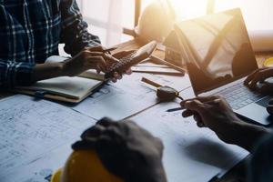 Image of engineering objects on workplace with three partners interacting on background photo