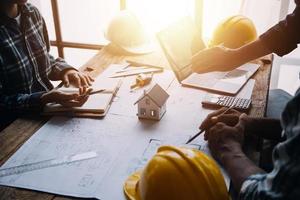 Image of engineering objects on workplace with three partners interacting on background photo