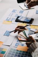 Close up ux developer and ui designer brainstorming about mobile app interface wireframe design on table with customer breif and color code at modern office.Creative digital development agency photo