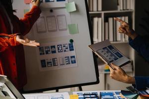 Close up ux developer and ui designer brainstorming about mobile app interface wireframe design on table with customer breif and color code at modern office.Creative digital development agency photo