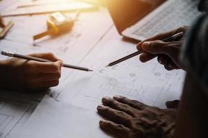Image of engineering objects on workplace with three partners interacting on background photo
