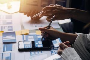 Close up ux developer and ui designer brainstorming about mobile app interface wireframe design on table with customer breif and color code at modern office.Creative digital development agency photo
