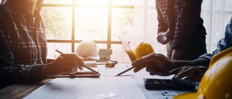 Image of engineering objects on workplace with three partners interacting on background photo
