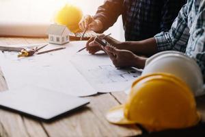 Image of engineering objects on workplace with three partners interacting on background photo
