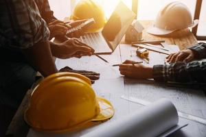Image of engineering objects on workplace with three partners interacting on background photo