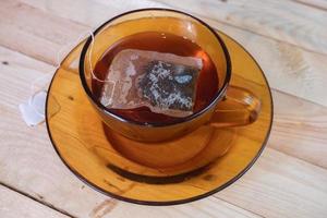 teabag in glass on wooden table photo