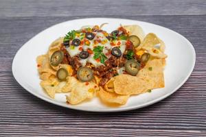 Mexican Famous Food Spicy Ground Beef Nachos. Heated crunchy tortilla chips with melted cheese and jalapeno served a snack food. photo