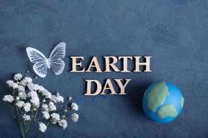 Earth day text with globe, flowers and butterfly. Happy Earth day concept flat lay, top view photo