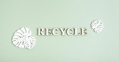 Recycle text from wooden letters top view on green background photo