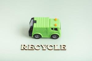 Recycle text. Toy garbage truck and recycle text on a green background photo