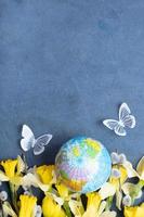 Globe, flowers and butterfly with copy space. Happy Earth day concept flat lay, top view. photo